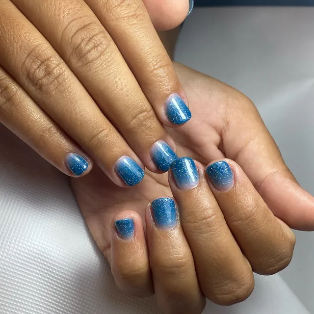 Unhas curtas com degradê azul e brilho